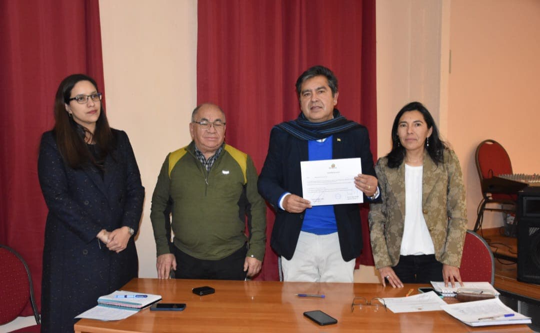 Cuatro participantes posan con un documento en una sala.
